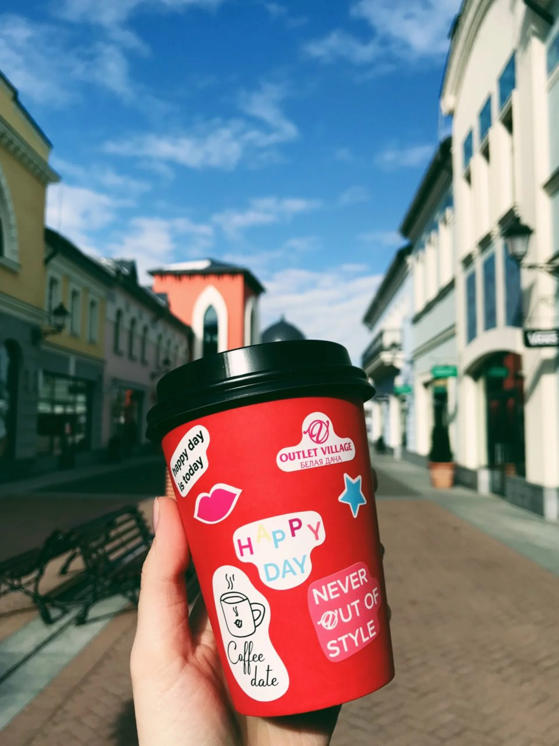 Branded coffee cup with stickers at Outlet Village
